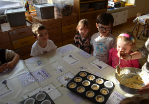 Dzieci z grupy IV nakładają ciasto dyniowe do papilotek