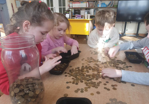 Dzieci z grupy IV segregują monety, co wcale nie jest łatwe