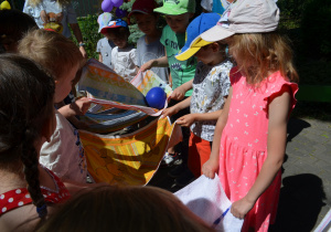 Dzieci z grupy III przekładają balon z wodą
