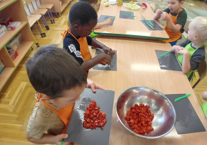 Dzieci z grupy III wrzucają do miski pokrojone pomidory
