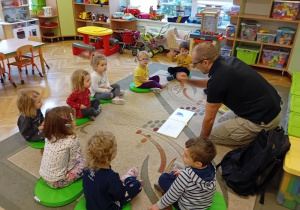 Dzieci z grupy 1 słuchają książki czytanej przez tatę Marcina